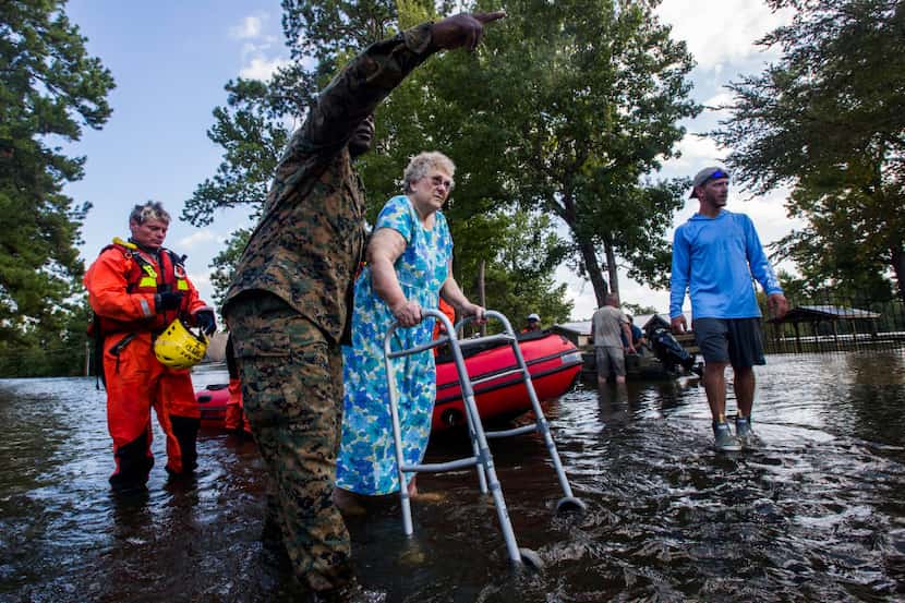 Navy Medic Gayakpa Komi, second from left, helps Sandra Griffin out of a rescue boat as...