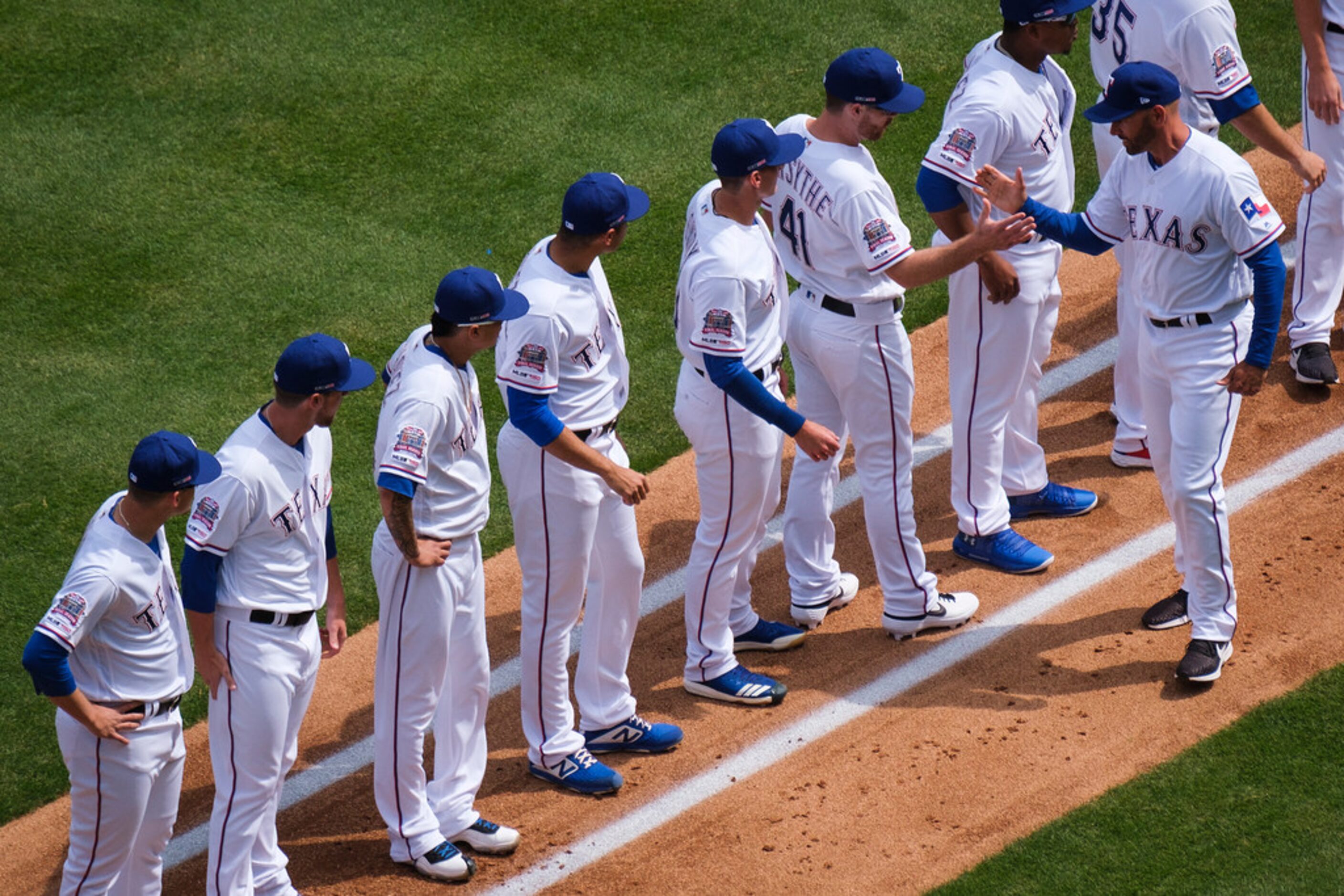 Texas Rangers manager Chris Woodward slaps hands with infielder Logan Forsythe as the teams...