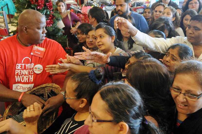 Donnell Allen, a sales associate at J.C. Penney, attempts to hand out coupon packets while...