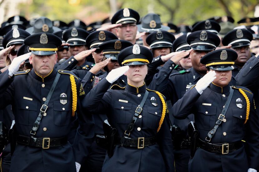 Dallas police officers salute as the casket of slain officer Michael Krol is carried out of...