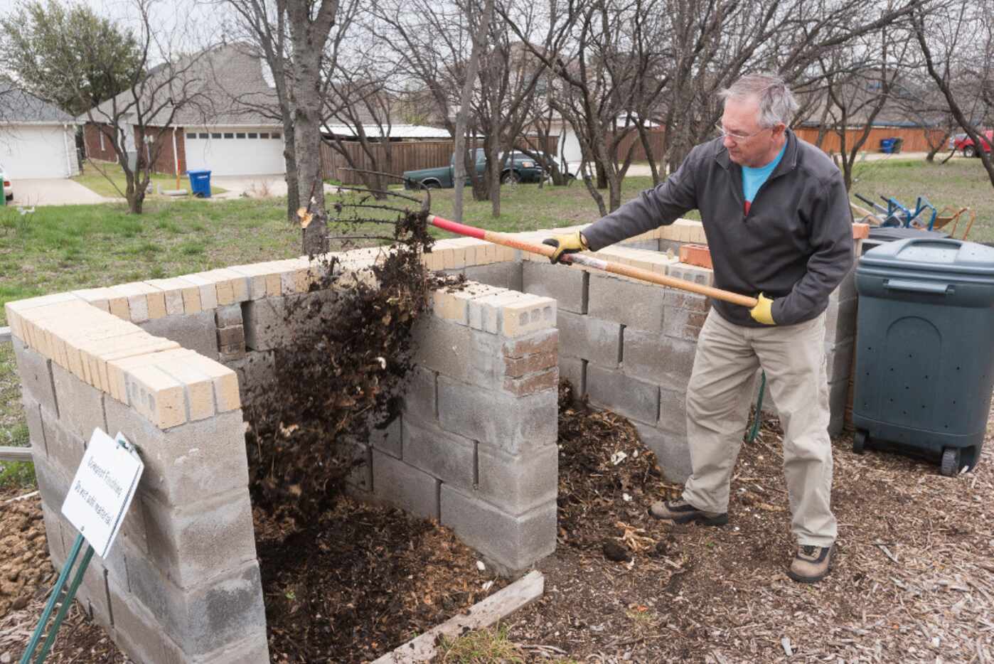 Willie Lane adds material to compost at the Giving Garden of Carrollton. Gardeners who...