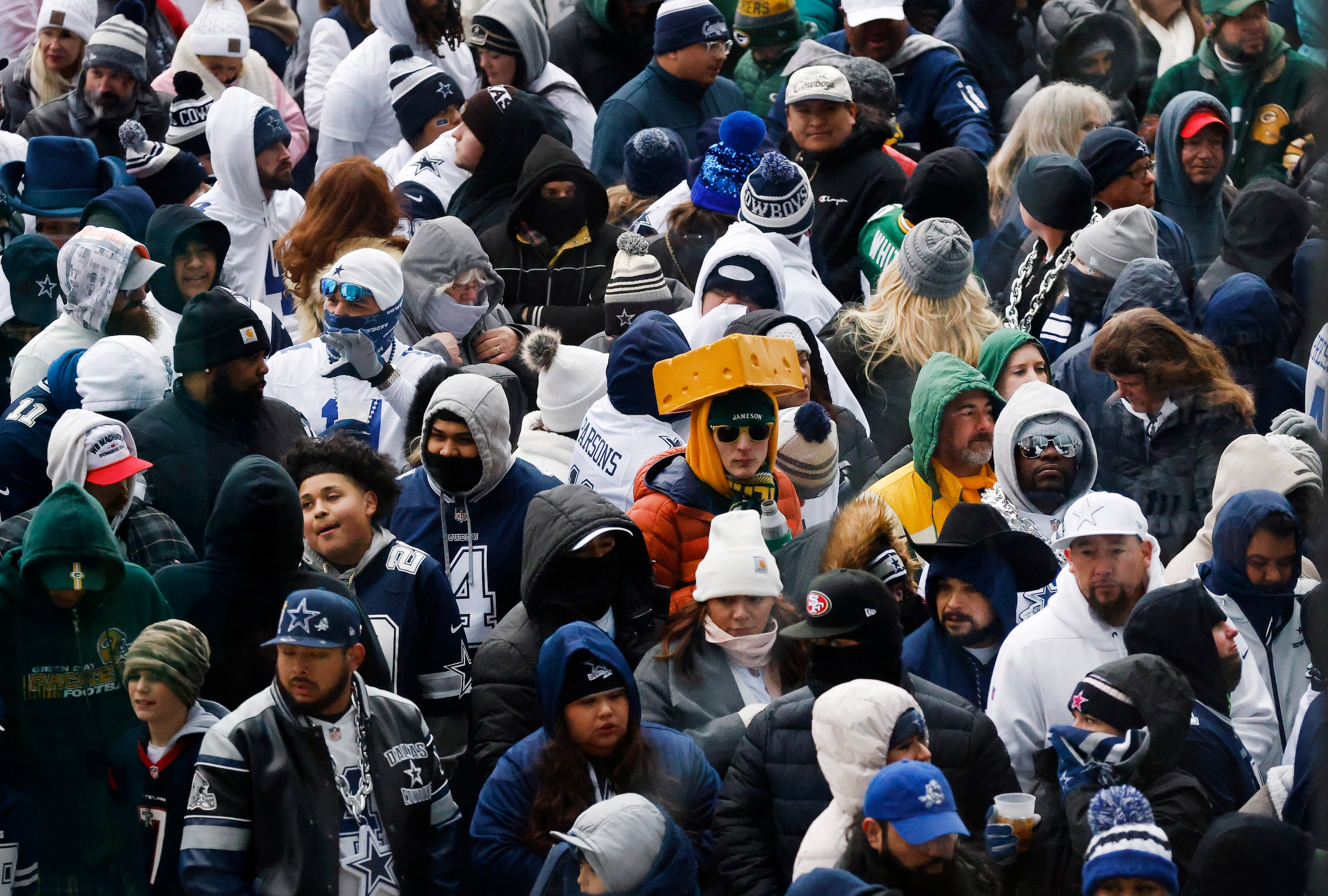 Dallas Cowboys and Green Bay Packers fans keep warm on the west plaza as they wait to get...