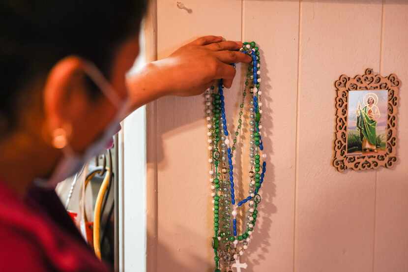 Jacoba arranges the rosaries hanging next to the altar that she has in her living room. She...