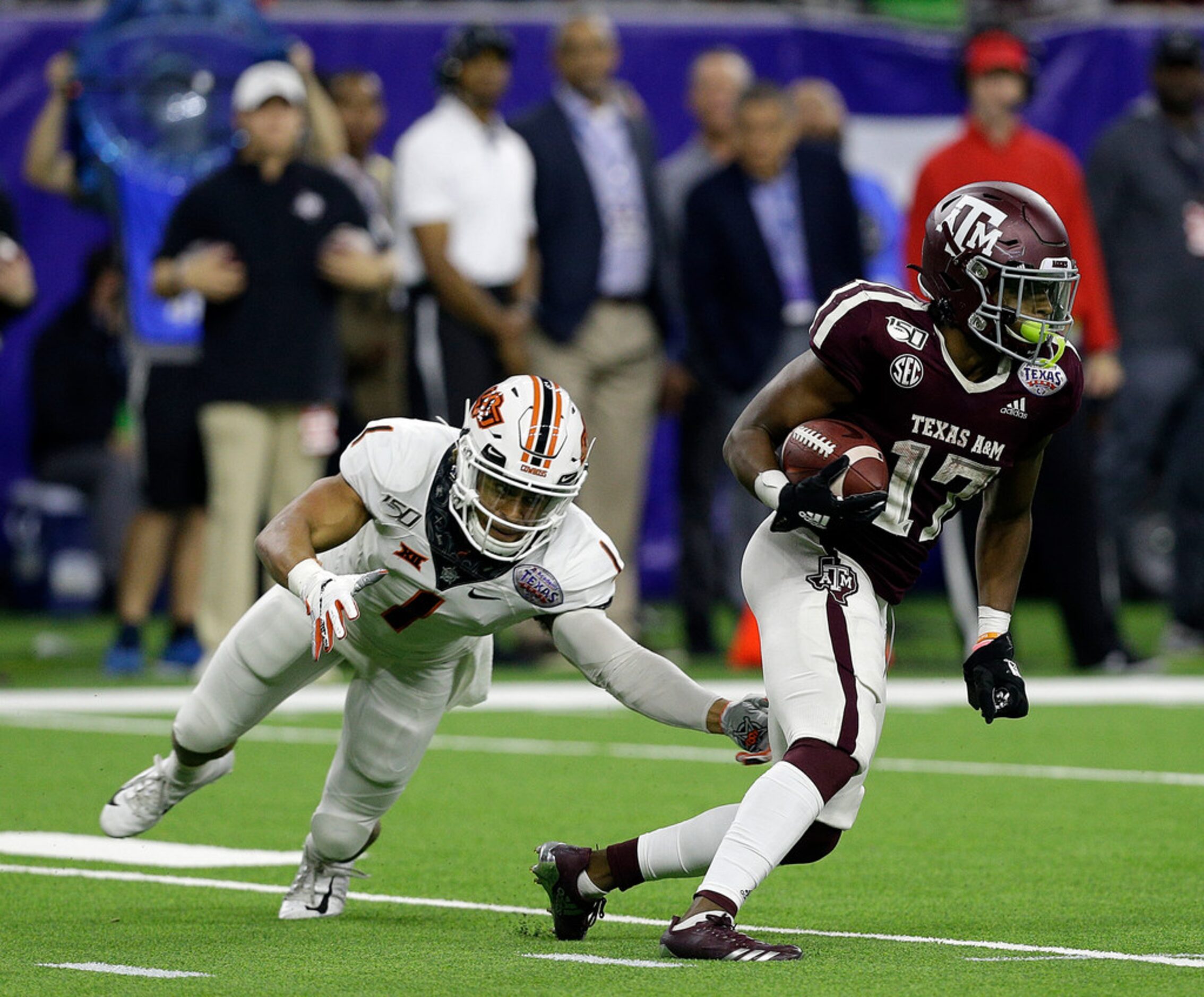 HOUSTON, TEXAS - DECEMBER 27: Ainias Smith #17 of the Texas A&M Aggies avoids the tackle...