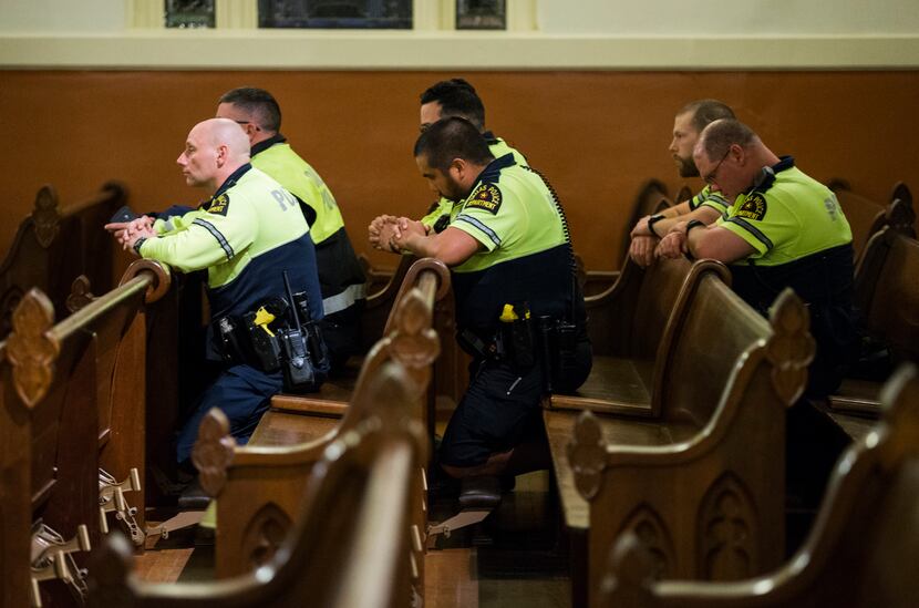 Dallas police officers kneel during a Mass in Spanish at the Cathedral Shrine of the Virgin...