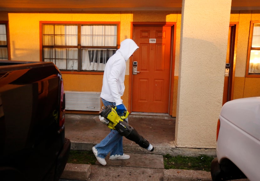 A maintenance man cleans the parking lot outside Room 105 of the Delux Inn on Royal Lane...