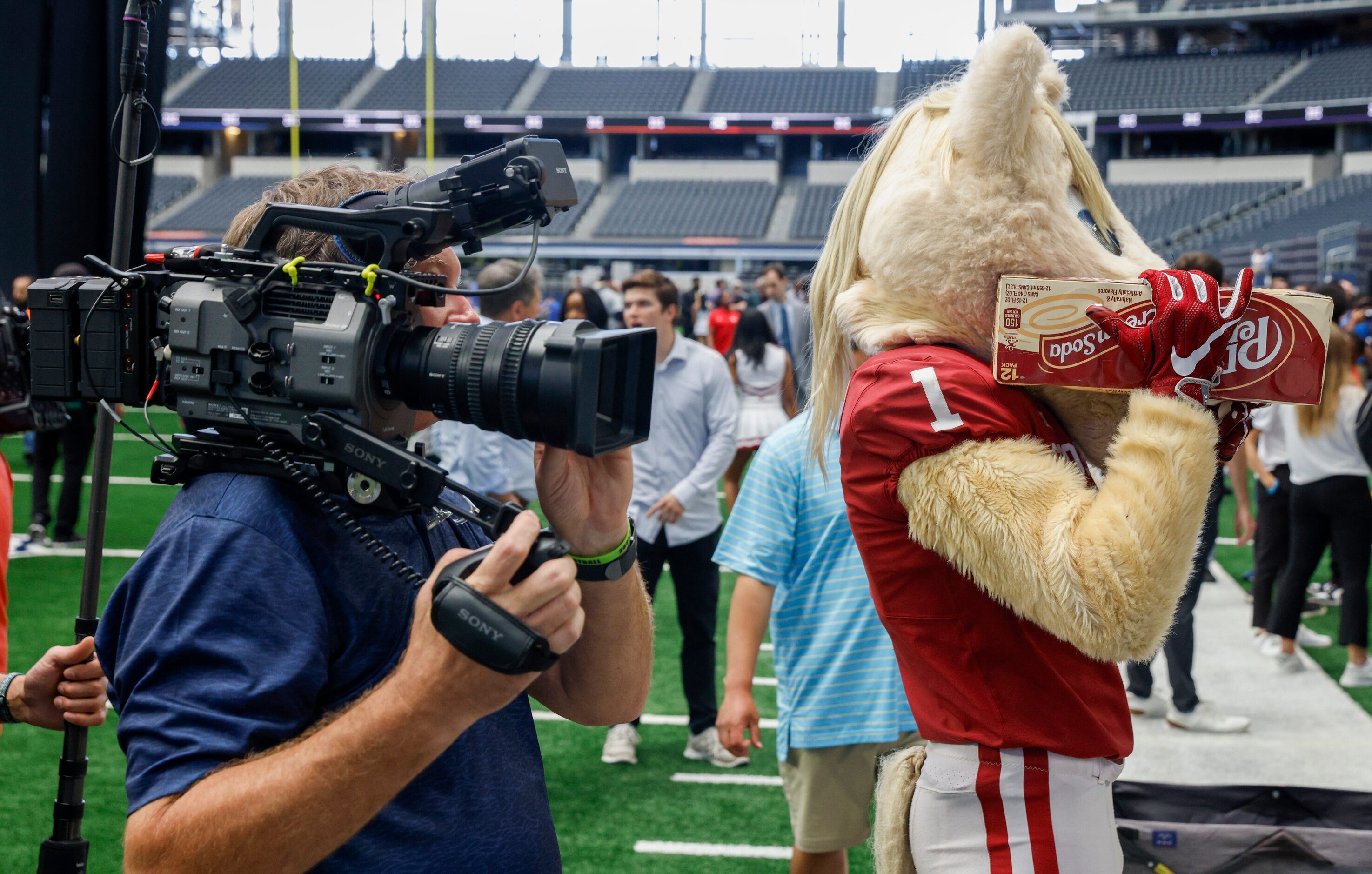 Oklahoma mascot Boomer holds up a case of Dr Pepper to mimic a videographer during the Big...