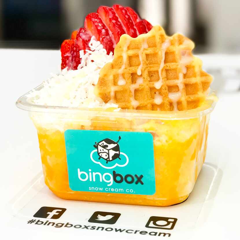 Mango snow cream topped with coconut flakes, a waffle crisp, strawberries and condensed milk...
