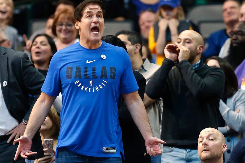 Dallas Mavericks owner Mark Cuban, left, reacts as his team plays the Indiana Pacers during...