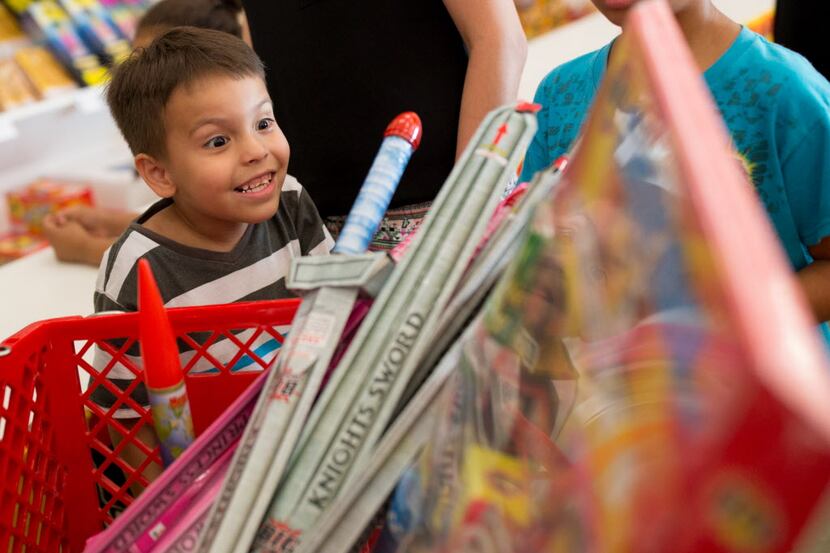 Damian Munoz, 5, of Garland peers into a cart full of fireworks while his family shops at...