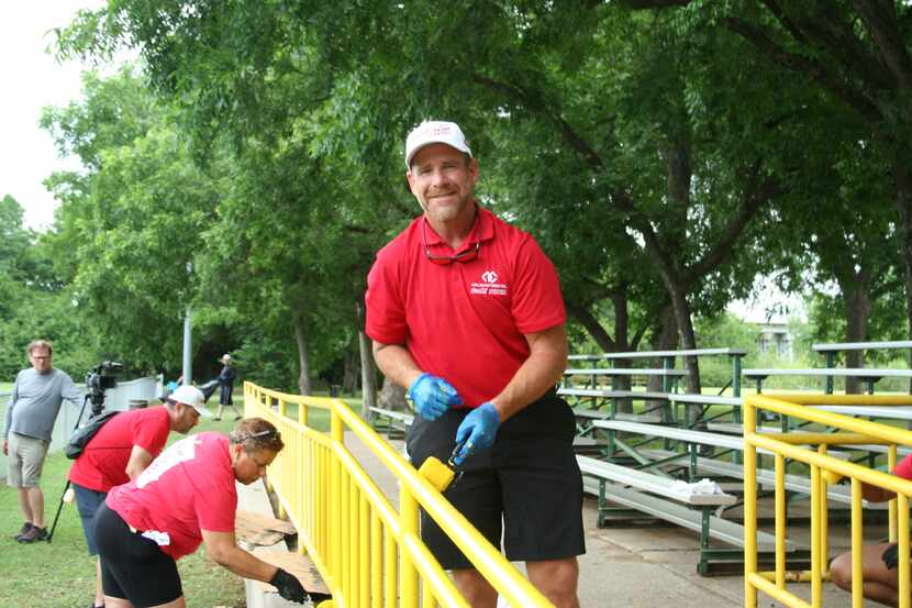 Coca-Cola Southwest Beverages employee in red polo shirt and black shorts paints a park...