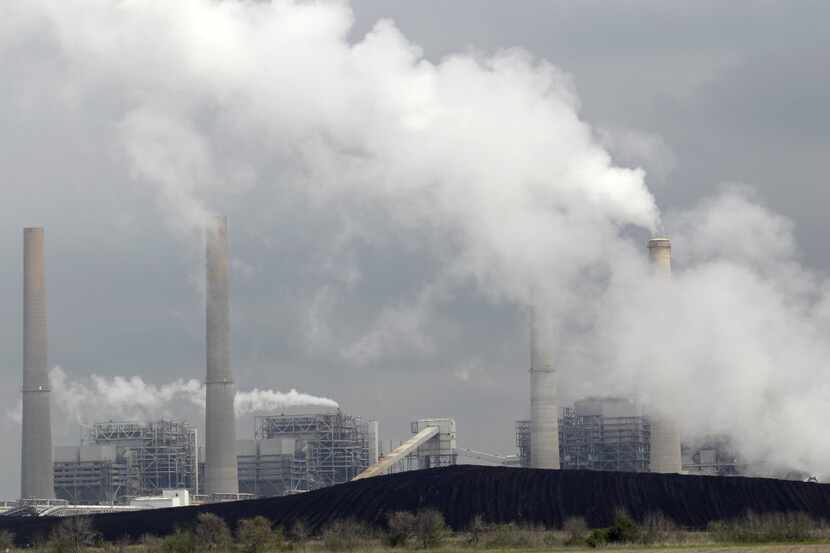  In this March 16, 2011 file photo, exhaust rises from smokestacks in front of piles of coal...
