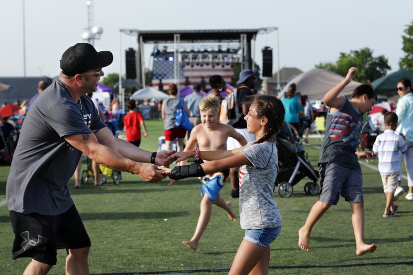 Ted Paulmeno, left, and 11-year-old Adriana Paulmeno dance to the music during the Allen USA...