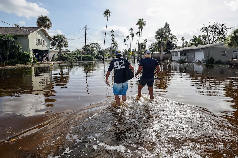 Thomas Chaves, left, and Vinny Almeida walk through floodwaters from Hurricane Helene in an...