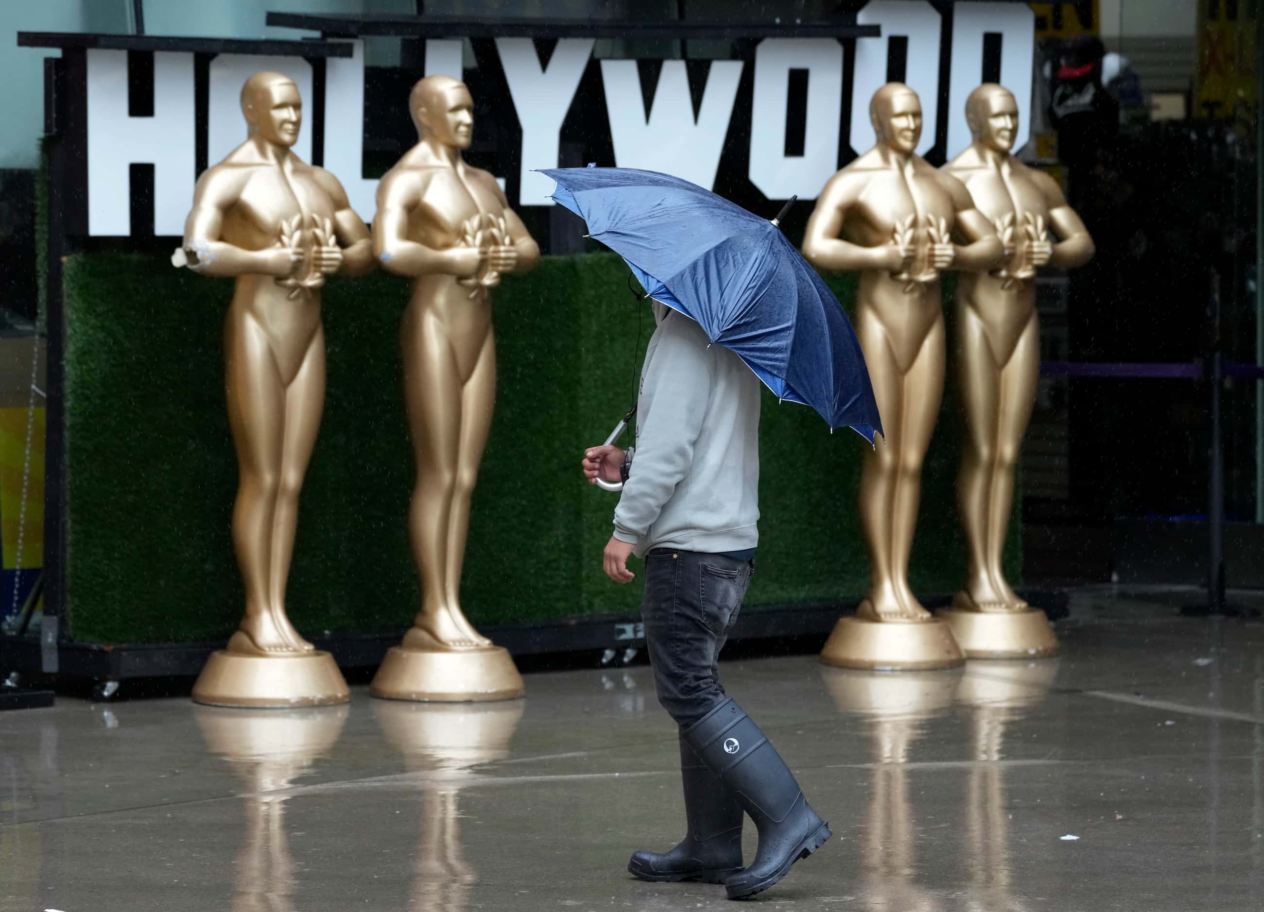 A pedestrian shields himself from strong winds and rain on Hollywood Boulevard during...