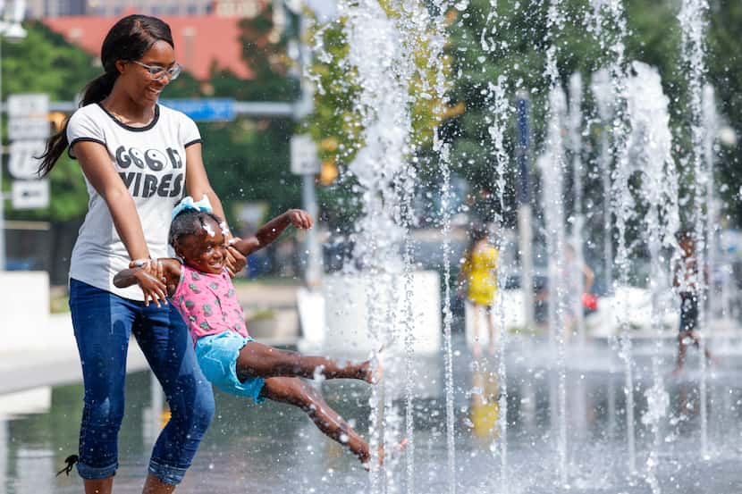 Aniya Hurse, left,, gives her cousin Heaven Reid, 3, a spin at a water fountain, Thursday,...