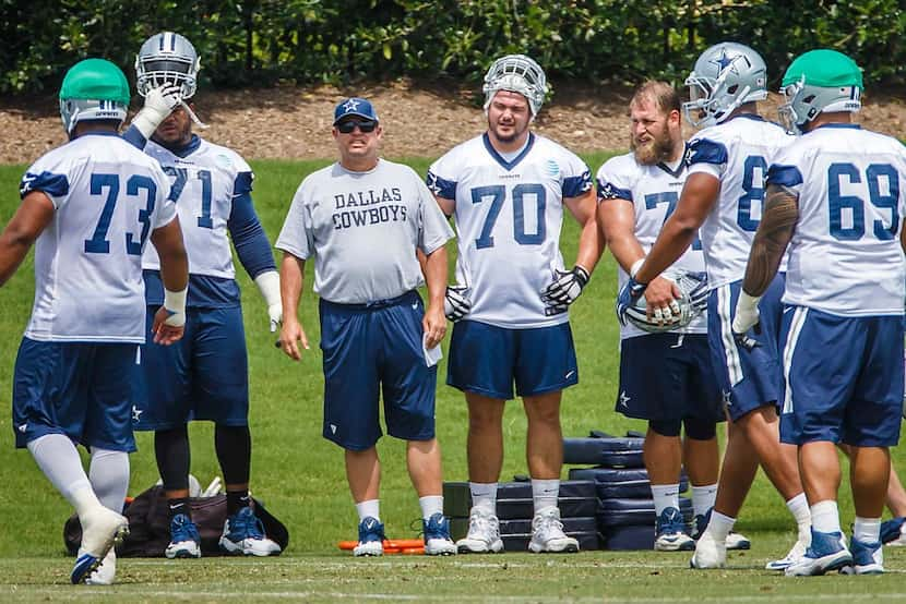 Cowboys offensive line coach Paul Alexander watches the team workout alongside tackle La'el...