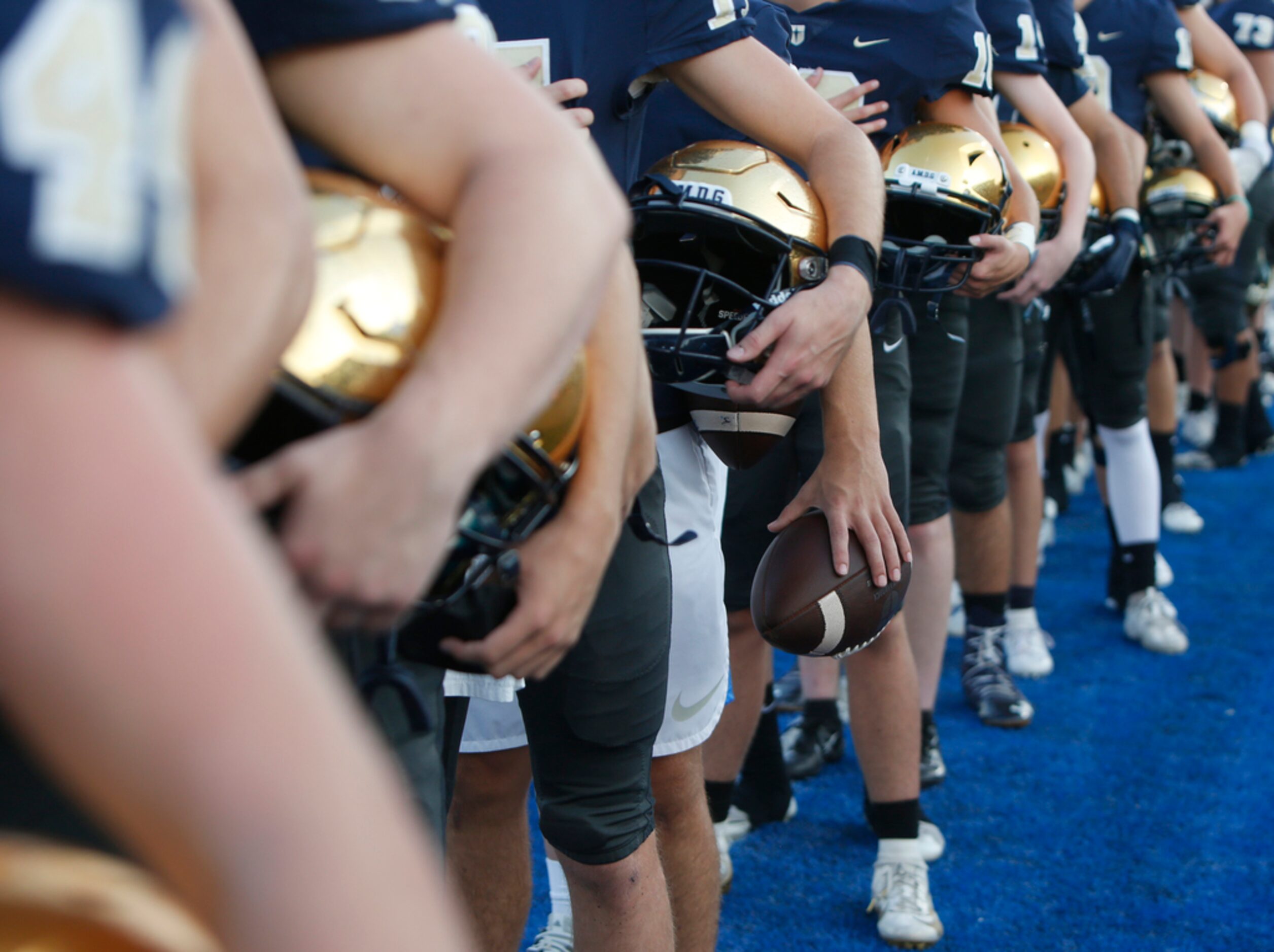 Members of the Jesuit varsity football team pause for the playing of the national anthem...