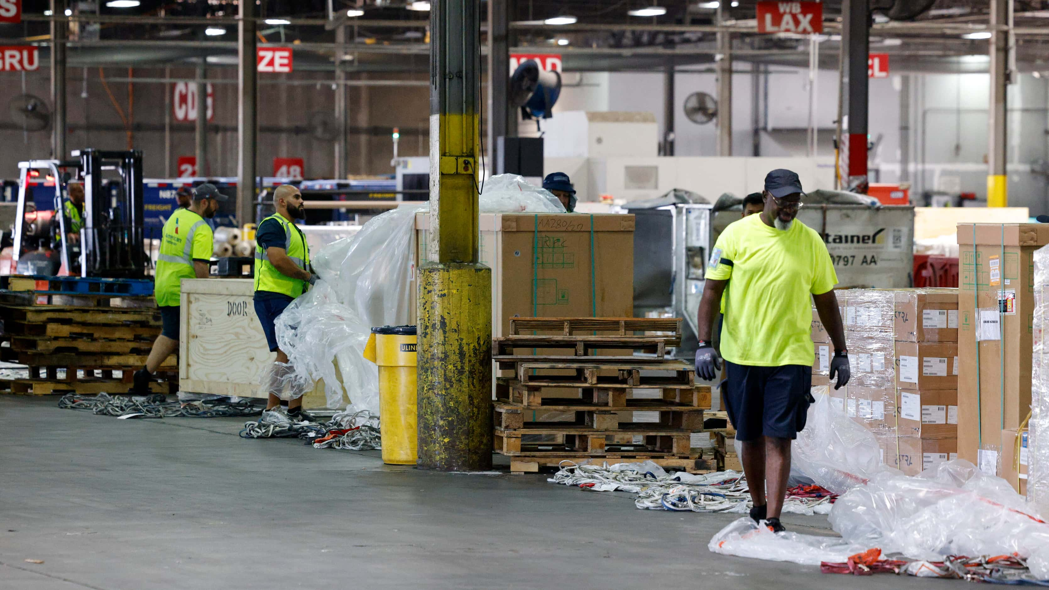 American Airlines cargo workers breakdown incoming cargo at a facility near the airfield,...