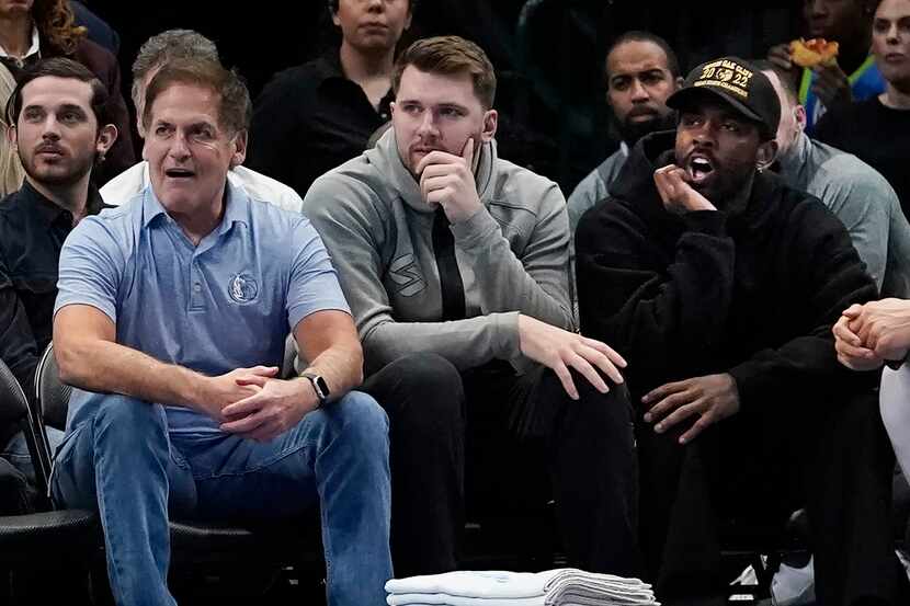 Dallas Mavericks team owner Mark Cuban, left, sits with players Luka Doncic, center, and...