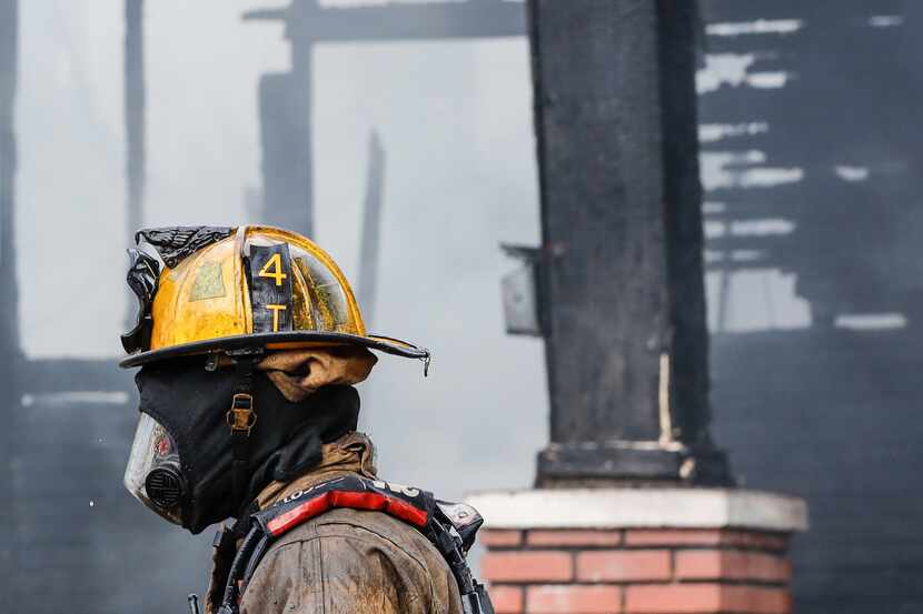 A Dallas firefighter stands in front of a burned house in Oak Cliff in November 2021. Dallas...