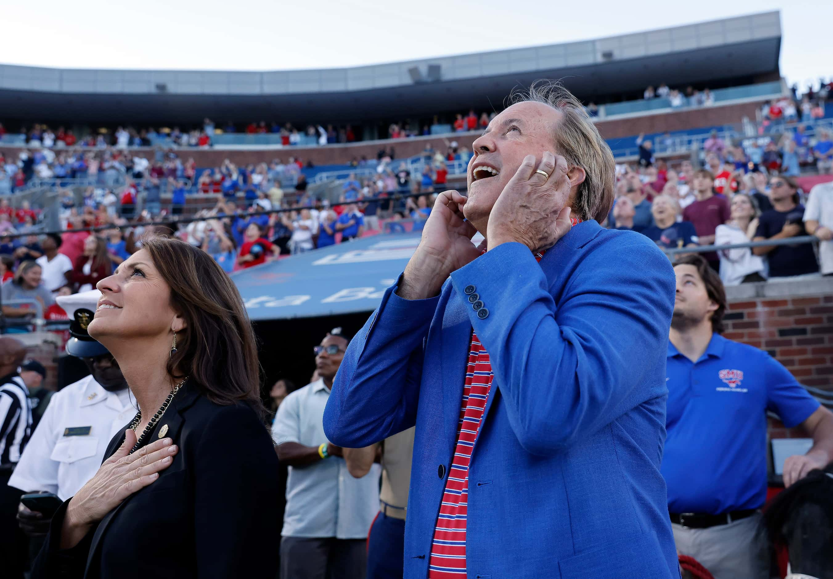 Texas Attorney General Ken Paxton covers his ears as a military flyover took place at Gerald...