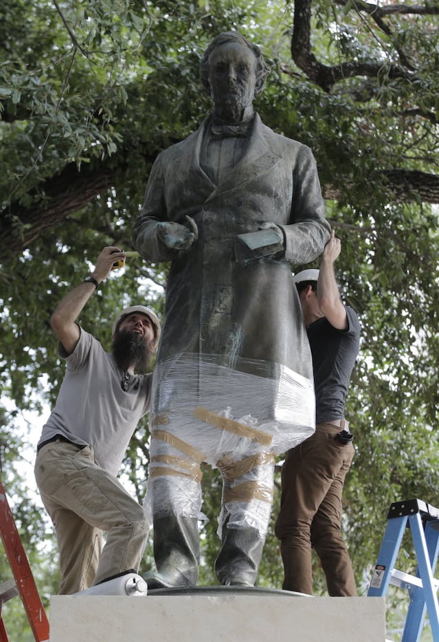 Workers wrap protective materials around a statue of Confederate President Jefferson Davis...