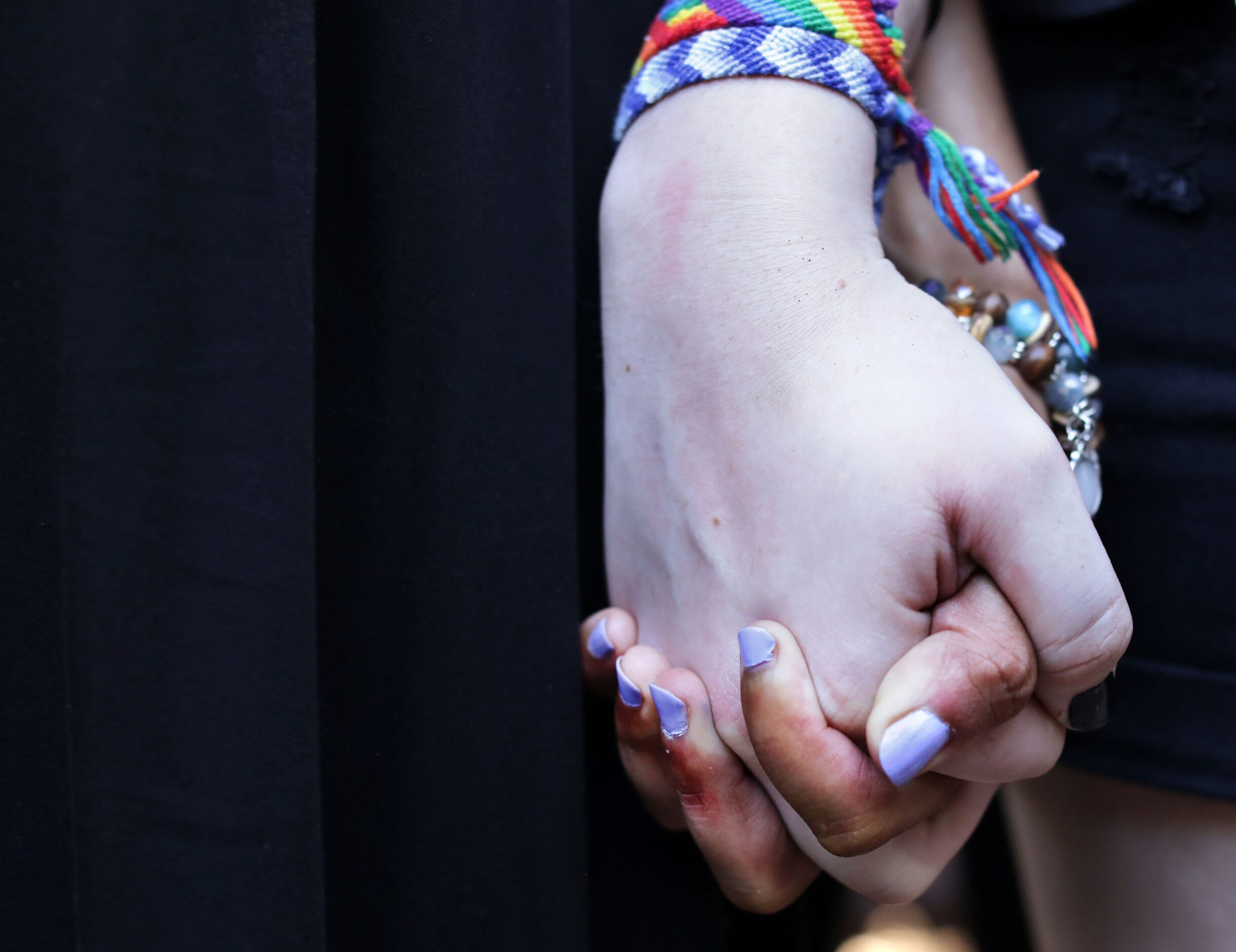 Ava McLeod, left, and Jacqueline Salfelder hold hands as protestors meet at the historic...