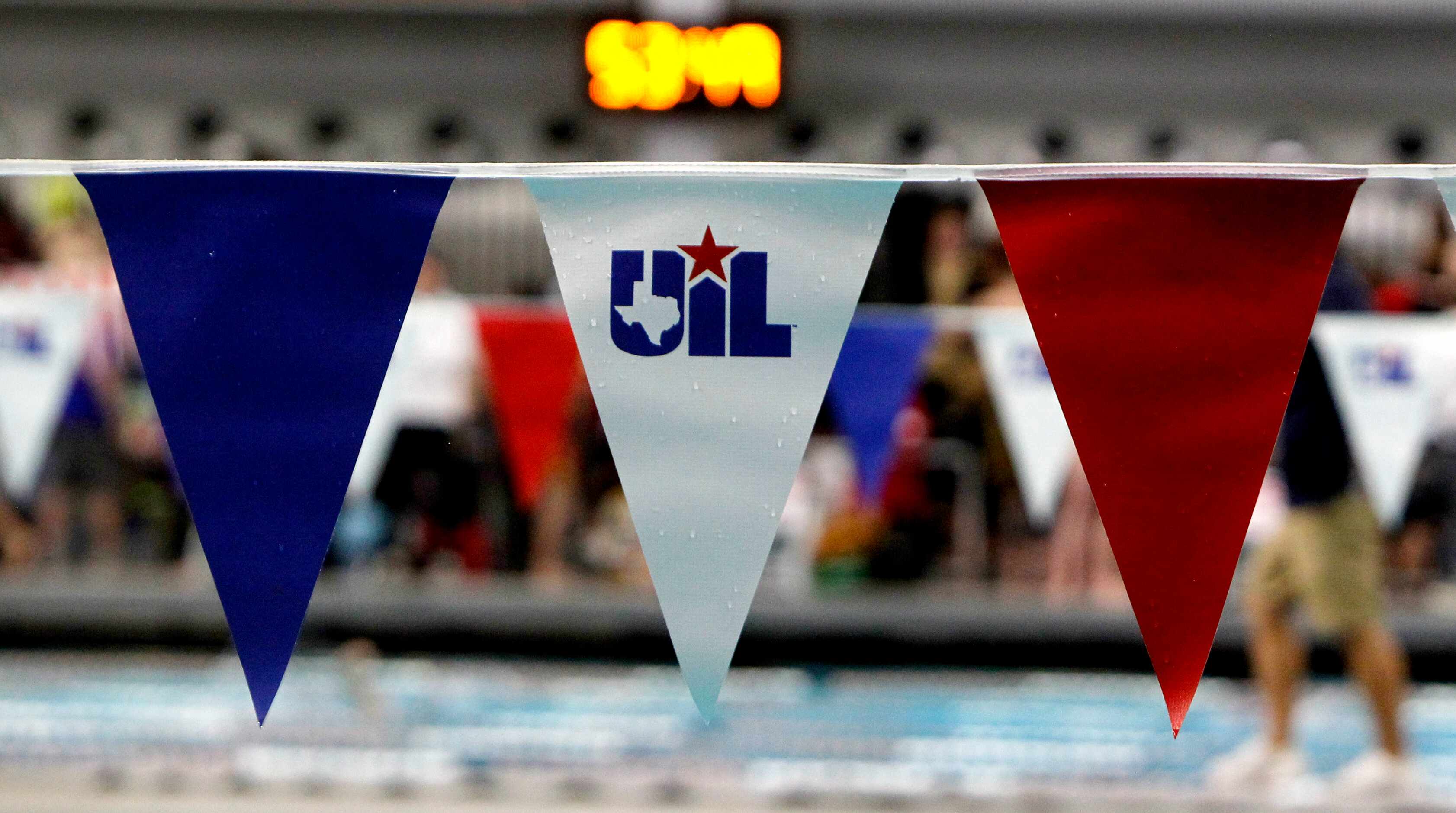 A UIL banner is draped above the swim lanes before the start of competition. The first day...