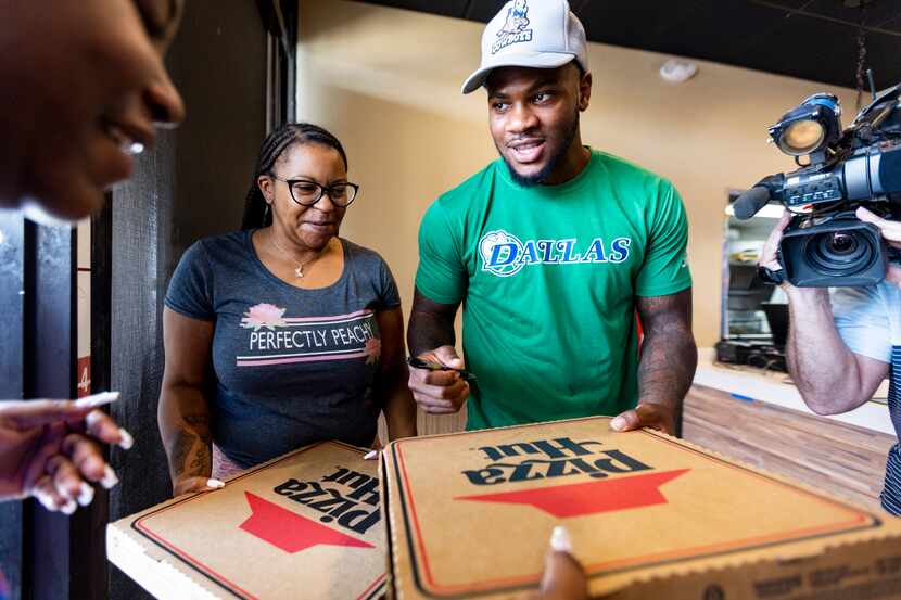 Dallas Cowboys linebacker Micah Parsons, right, autographs free pizzas that he handed out to...