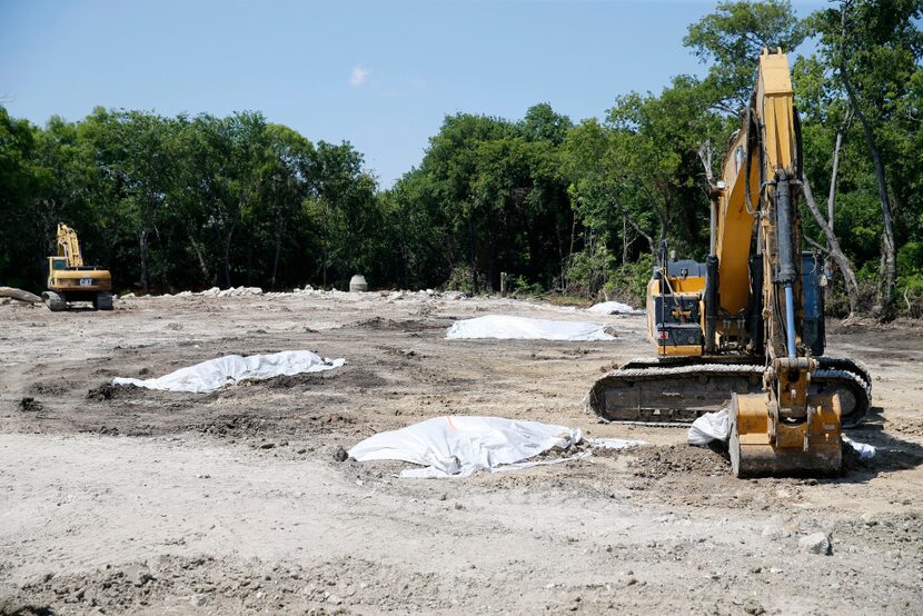 Construction crews excavate in a vacant lot across the street from the old Exide...