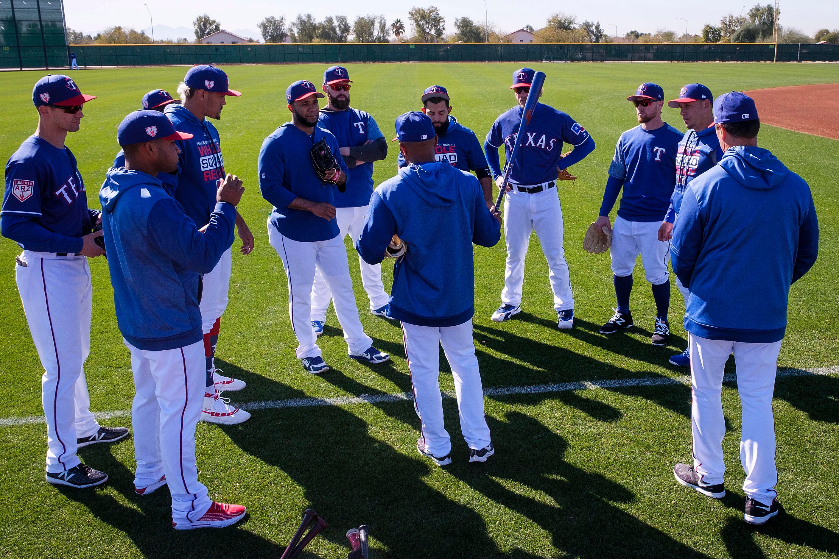 Texas Rangers position players huddle around third base coach Tony Beasley before beginning...