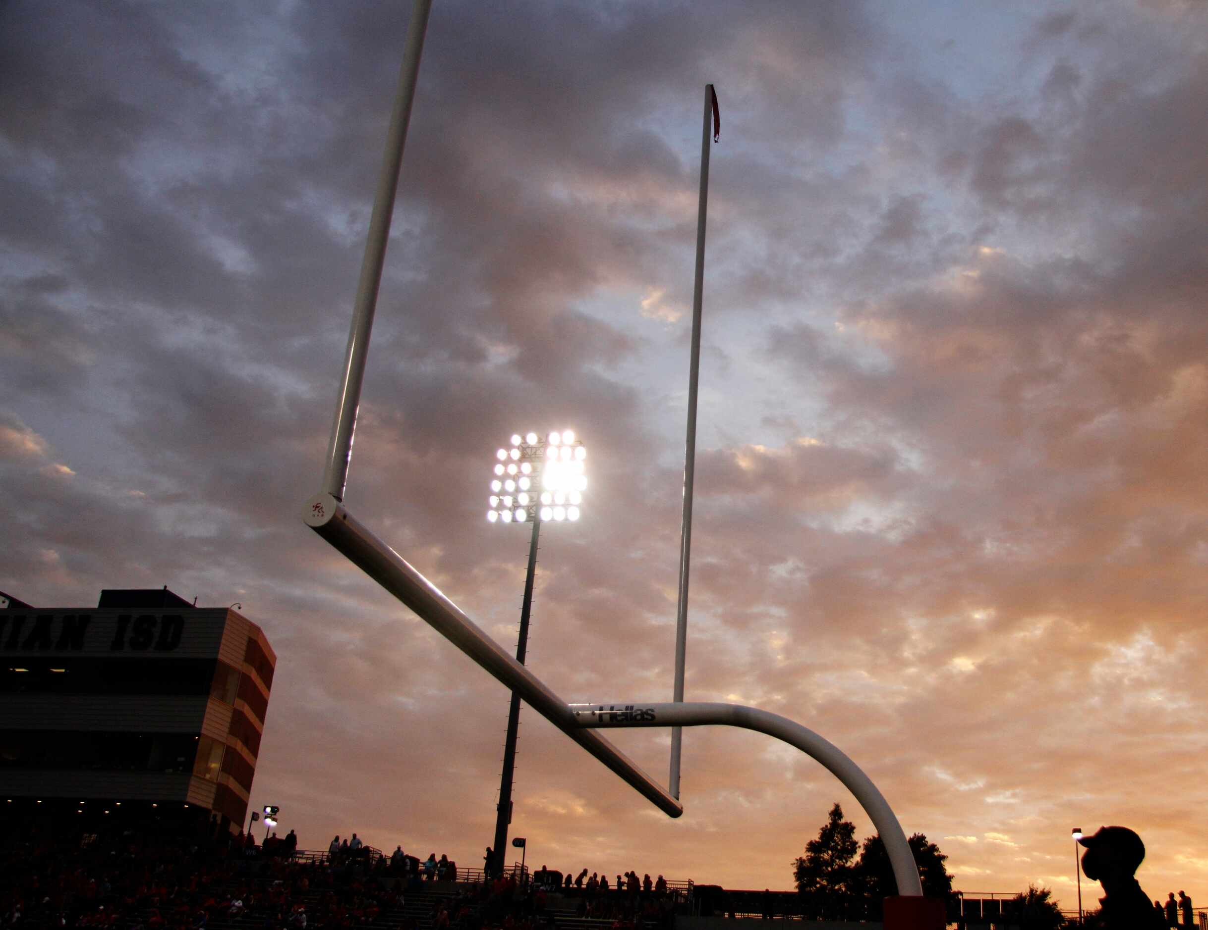 A setting sun greets the opening of the second quarter of action between Midlothian Heritage...