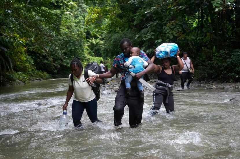 Migrantes haitianos vadean un río en la selva del Darién el 15 de octubre de 2022, en un...