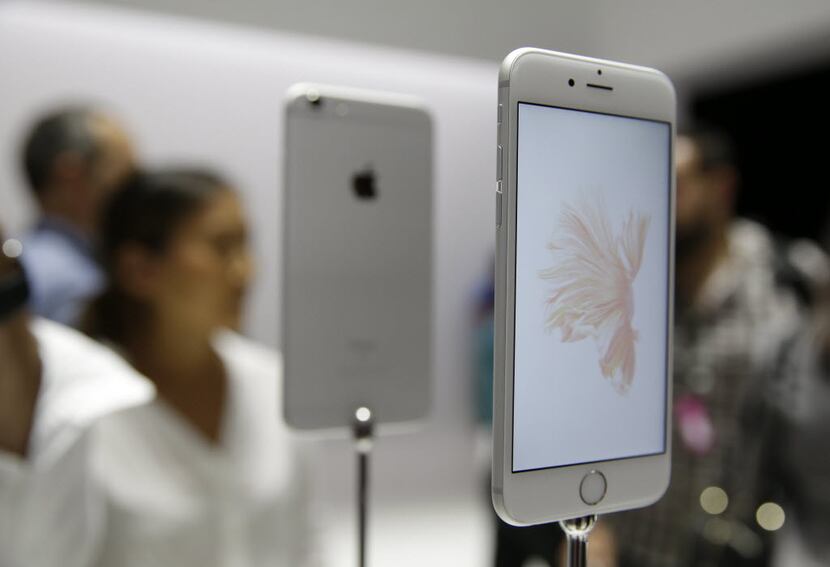 People look over the new Apple iPhone 6s models during a product display.
