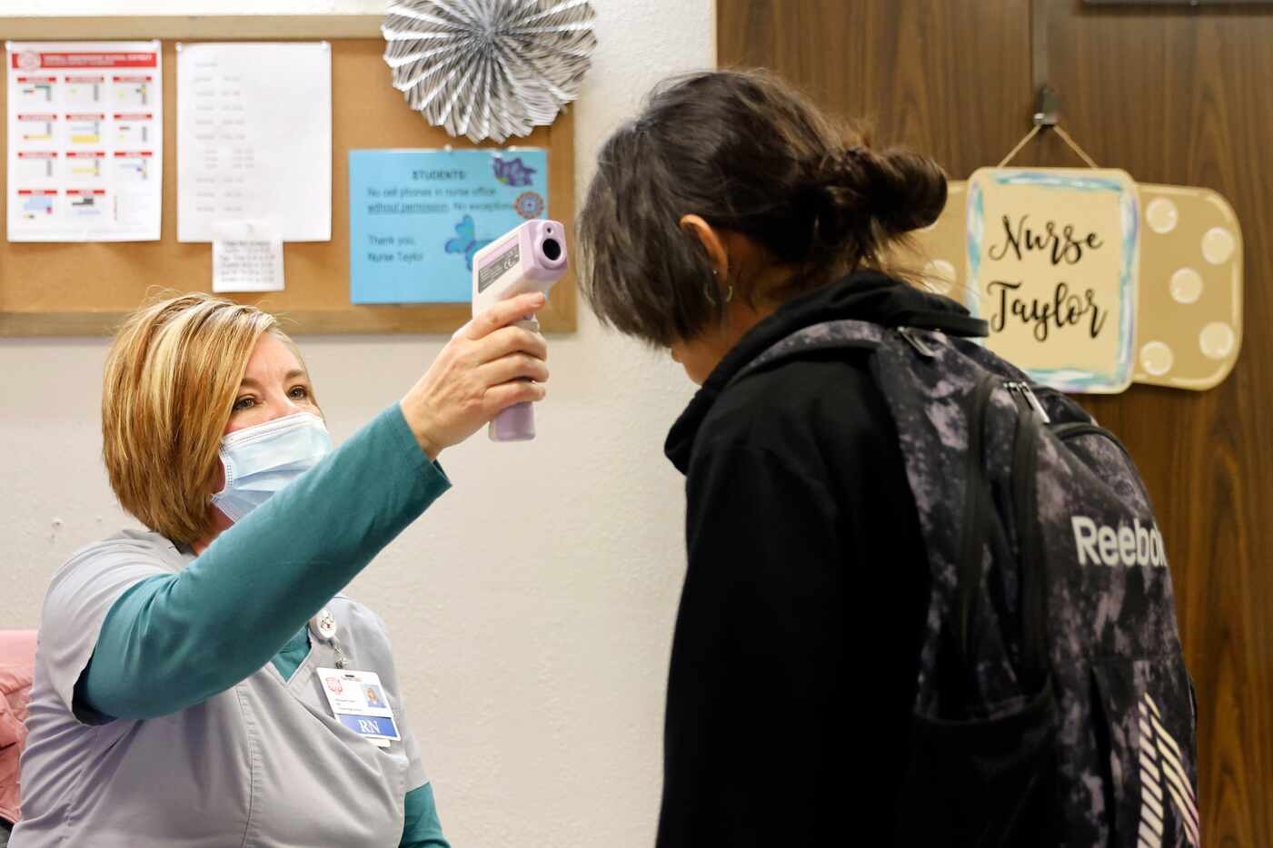 RN Stephanie Taylor checks a student’s temperature at Terrell Sr. High’s east campus office...
