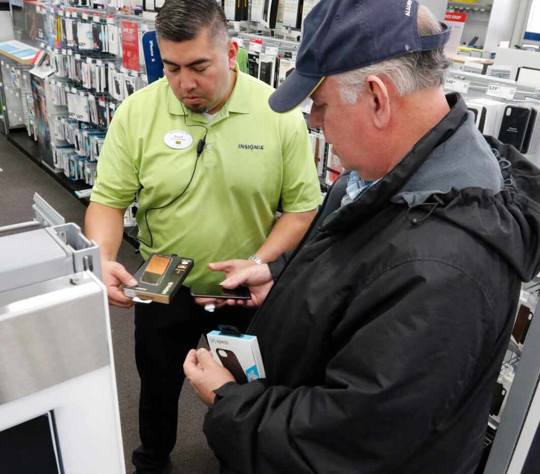 Best Buy General Manager David Gonzales, left, helps Gerald Lindsey, right, find an iPhone...