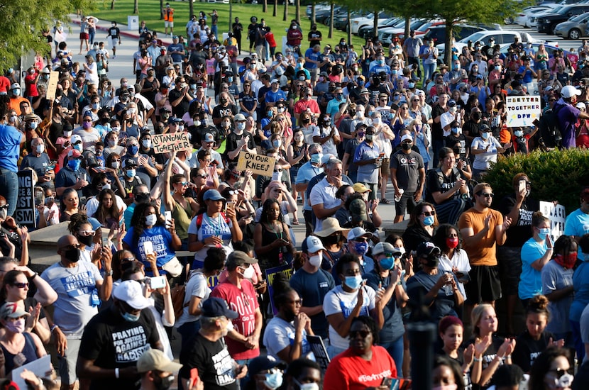 People clap after singing a song during a McKinney demonstration organized by Collin County...