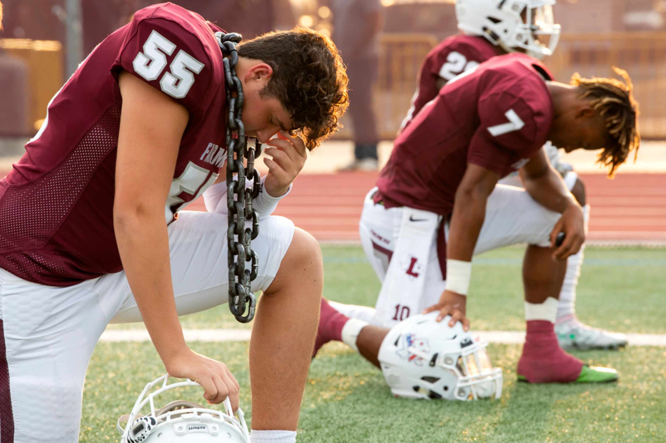 Lewisville seniors Jeremy Marquez (55) and Covasean Pryor (7) pause to pray before a high...