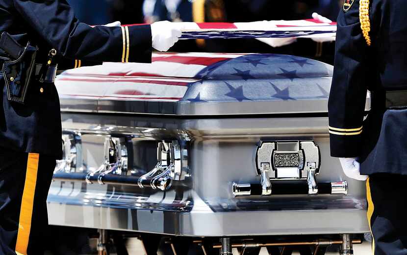 The colors of the Stars and Stripes were reflected on the surface of the coffin as the...