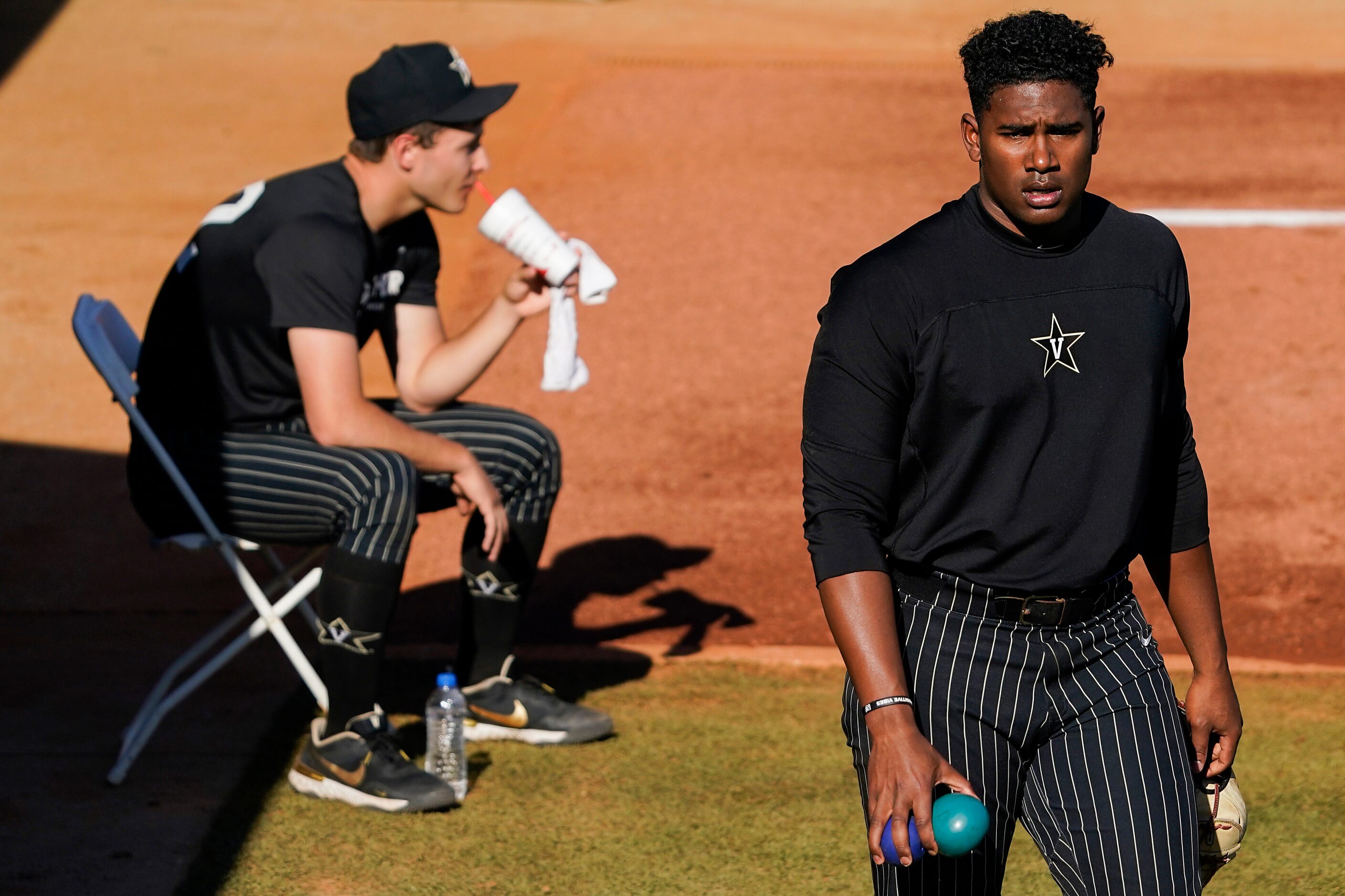 Vanderbilt pitcher Kumar Rocker warms up as fellow pitcher Jack Leiter sips a smoothie in...