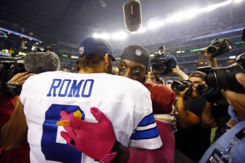 Dallas Cowboys quarterback Tony Romo (9) hugs Washington Redskins quarterback Robert Griffin...