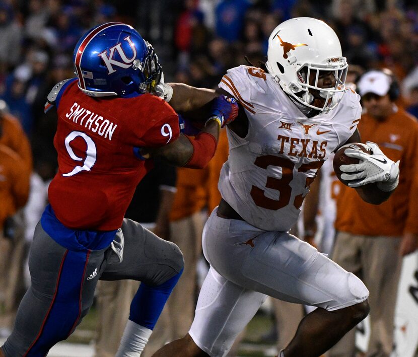 LAWRENCE, KS - NOVEMBER 19:  D'Onta Foreman #33 of the Texas Longhorns stiff arms Fish...