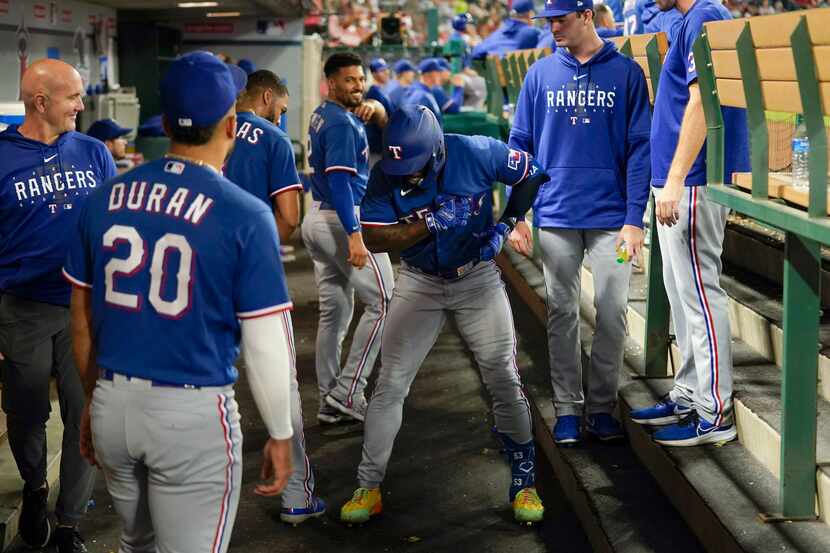 Texas Rangers' Adolis Garcia, center, dances in the dugout as he celebrates his home run...
