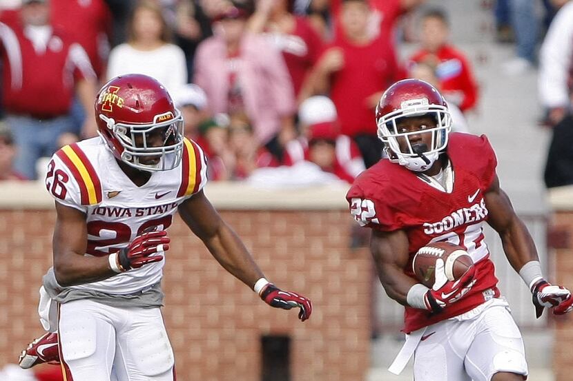 Oklahoma running back Roy Finch (22) carries the ball as Iowa State's Deon Broomfield chases...