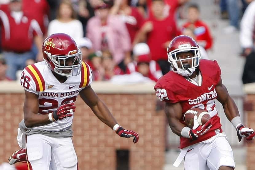 Oklahoma running back Roy Finch (22) carries the ball as Iowa State's Deon Broomfield chases...