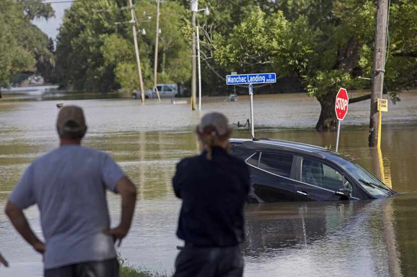 Vecinos contemplan un vehículo sumergido en el agua en la carretera Old Jefferson, en...