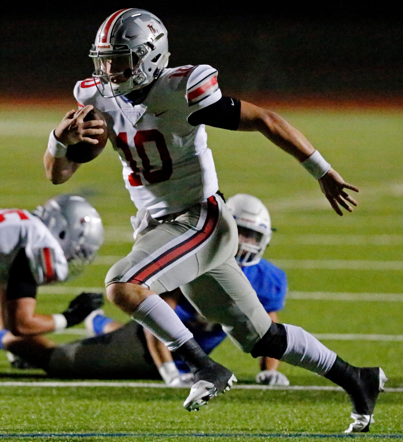 Lovejoy High School quarterback R.W. Rucker (10) looks for room to run during the first half...