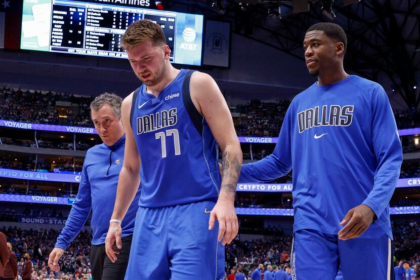 Dallas Mavericks guard Luka Doncic (77) limps off the court after injuring his lower left...