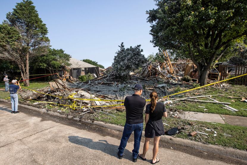 Theo Laskaris, center, and Virginia French, right, examine the damage at the site of a house...